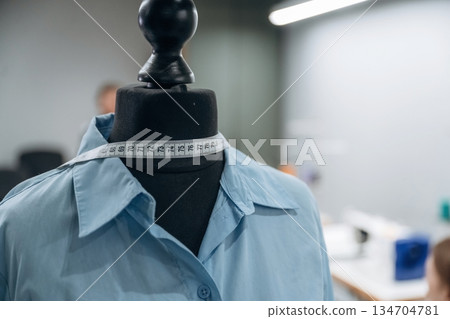 Tailor mannequin in blue shirt is in measuring tape Tailor mannequin in blue shirt is in measuring tape 134704781