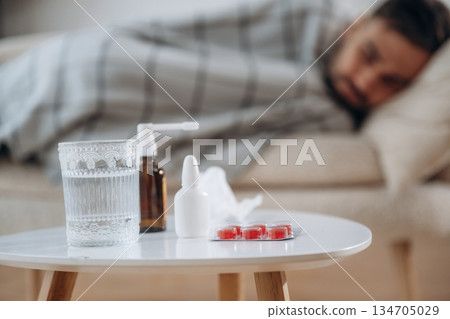 Water, spray and pills on the table. Sick man is feeling bad at home 134705029