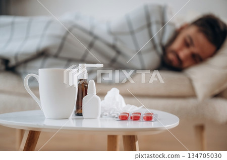 Water, spray and pills on the table. Sick man is feeling bad at home 134705030