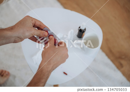 Guy is sitting and taking a pills, feeling sick, bad 134705033