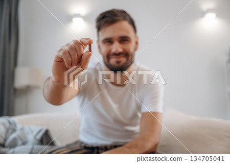 Positive smiling man is sitting holding pill, conception of medicine 134705041