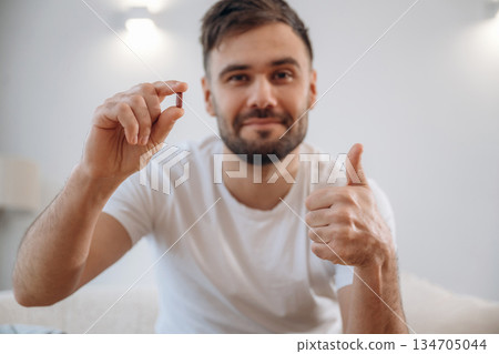 Positive smiling man is sitting holding pill, conception of medicine 134705044