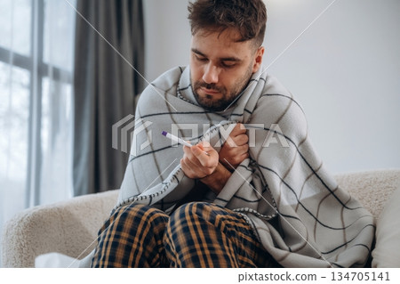 Checking body temperature with thermometer. Sick man is feeling bad at home Checking body temperature with thermometer. Sick man is feeling bad at home 134705141