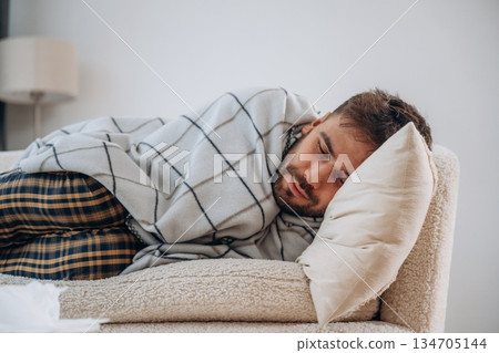 Cold, lying down under the blanket. Sick man is feeling bad at home Cold, lying down under the blanket. Sick man is feeling bad at home 134705144