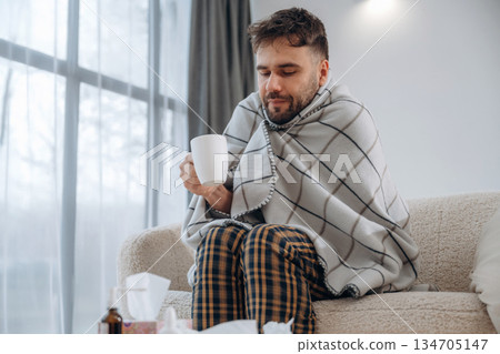 Cup in hand, drinking. Sick man is feeling bad at home Cup in hand, drinking. Sick man is feeling bad at home 134705147