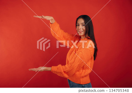 Invisible object in hands, copy space. Young beautiful woman is against background 134705348