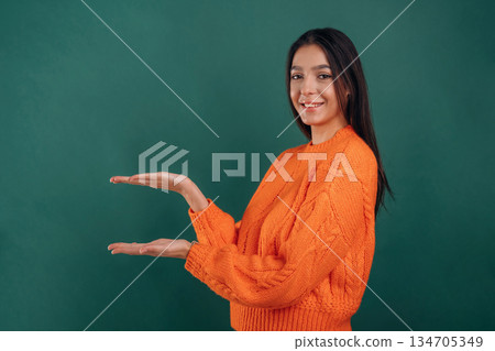 Invisible object in hands, copy space. Young beautiful woman is against background 134705349