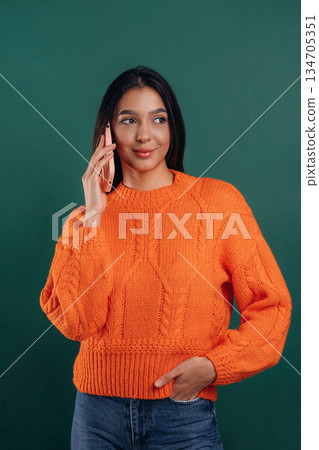 Talking by phone. Young beautiful woman is against background Talking by phone. Young beautiful woman is against background 134705351