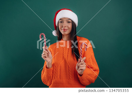 Christmas sweet candies, in Santa hat. Young beautiful woman is against background 134705355