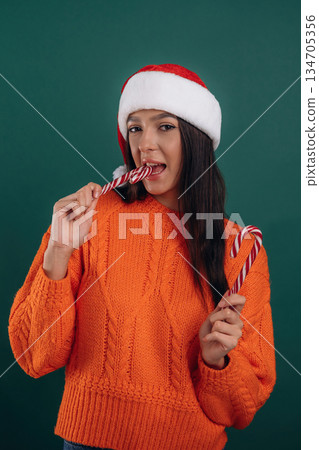 Christmas sweet candies, in Santa hat. Young beautiful woman is against background 134705356