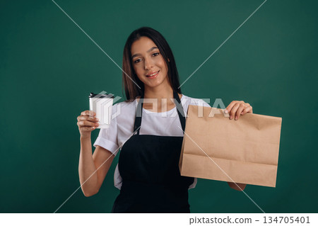 Your order is ready, with coffee. Young beautiful barista is against background Your order is ready, with coffee. Young beautiful barista is against background 134705401