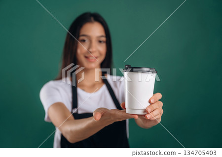 Your order is ready, with coffee. Young beautiful barista is against background Your order is ready, with coffee. Young beautiful barista is against background 134705403