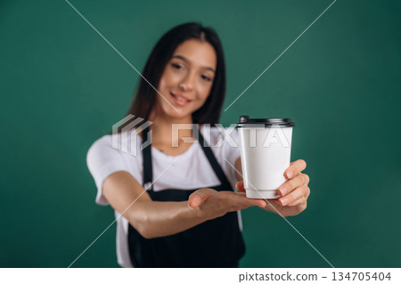 Your order is ready, with coffee. Young beautiful barista is against background Your order is ready, with coffee. Young beautiful barista is against background 134705404