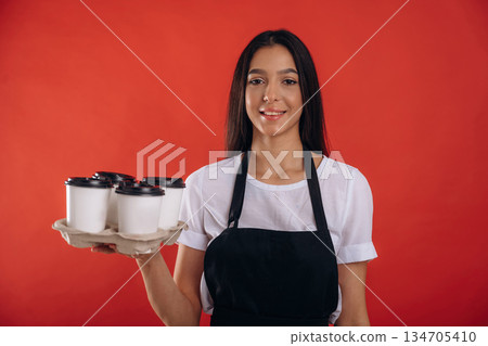 Many of the drinks, cups, ready. Young beautiful barista is against background Many of the drinks, cups, ready. Young beautiful barista is against background 134705410