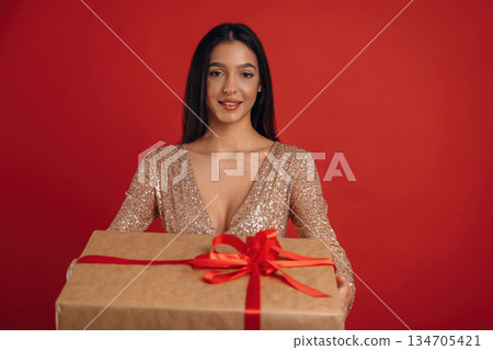 Celebration of new year, with gift. Young elegant woman is against background 134705421