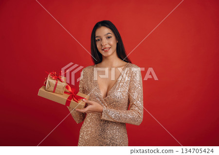 Celebration of new year, with gift. Young elegant woman is against background Celebration of new year, with gift. Young elegant woman is against background 134705424