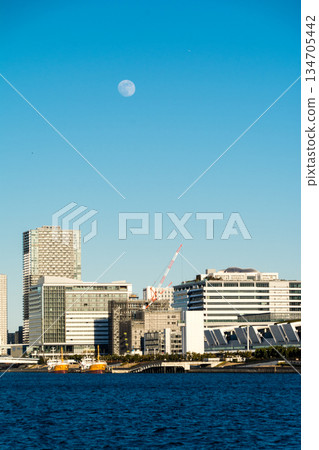 The vast waters of Tokyo Bay near Odaiba under the clear blue sky and moonlit daytime skyline, with Tokyo's skyscrapers visible in the distance The vast waters of Tokyo Bay near Odaiba under the clear blue sky and moonlit daytime skyline, with Tokyo's skyscrapers visible in the distance 134705442