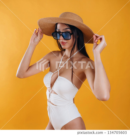 Side view, standing, in sunglasses and straw hat. Young beautiful tourist woman is against background Side view, standing, in sunglasses and straw hat. Young beautiful tourist woman is against background 134705603