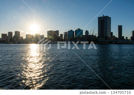 The vast waters of Tokyo Bay near Odaiba under the bright blue sky and dazzling sun, with Tokyo's skyscrapers visible in the distance 134705710