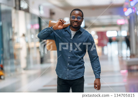 Walking and holding shopping bags. Black man is in the hall of the supermarket 134705815