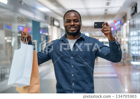 Credit card for shopping. Black man is in the hall of the supermarket Credit card for shopping. Black man is in the hall of the supermarket 134705903