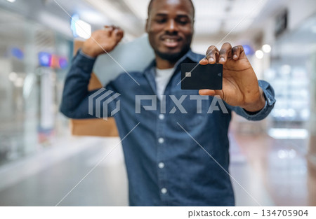 Credit card for shopping. Black man is in the hall of the supermarket Credit card for shopping. Black man is in the hall of the supermarket 134705904
