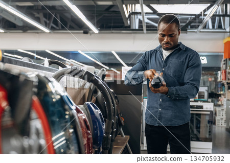 Vacuum cleaners. Man in a home appliance store Vacuum cleaners. Man in a home appliance store 134705932