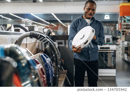 Automatic vacuum cleaner in hands. Man in a home appliance store Automatic vacuum cleaner in hands. Man in a home appliance store 134705942