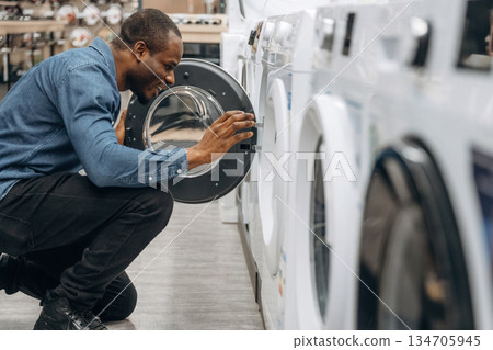 By washing machine. Man in a home appliance store By washing machine. Man in a home appliance store 134705945