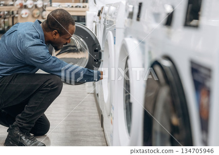 By washing machine. Man in a home appliance store By washing machine. Man in a home appliance store 134705946