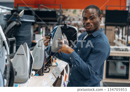 Clothes iron in hands. Man in a home appliance store 134705953