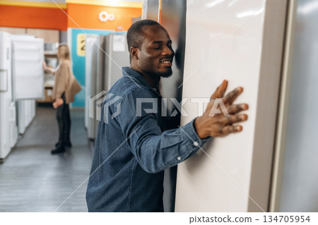 Man with woman are choosing fridge in the shop Man with woman are choosing fridge in the shop 134705954