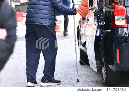 End of the year cityscape in Tokyo, Japan. Aging society. An elderly woman can't get a taxi so she calls one by cell phone. A man with a cane has difficulty walking... 134705984