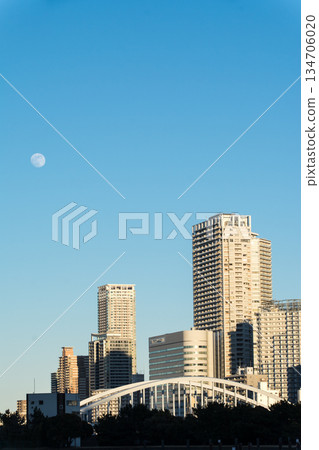 The vast waters of Tokyo Bay near Odaiba under the clear blue sky and moonlit daytime skyline, with Tokyo's skyscrapers visible in the distance The vast waters of Tokyo Bay near Odaiba under the clear blue sky and moonlit daytime skyline, with Tokyo's skyscrapers visible in the distance 134706020