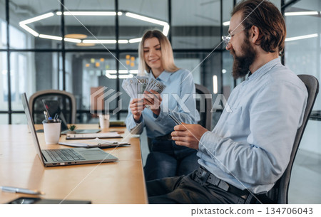 Counting money. Man and woman are in the office together 134706043