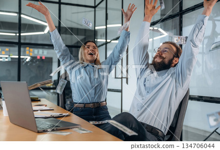Throwing lot of money up in the air. Man and woman are in the office together 134706044