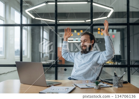 Celebrating success, hands up. Businessman is working in the office 134706136