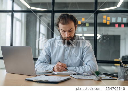 Front view, by laptop. Businessman is working in the office Front view, by laptop. Businessman is working in the office 134706140