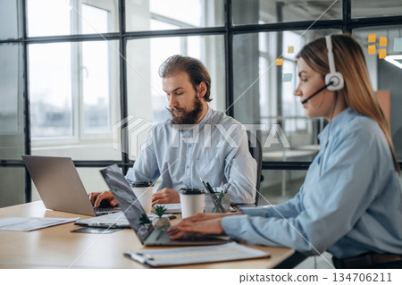Working by laptops. Man and woman are in the office together Working by laptops. Man and woman are in the office together 134706211