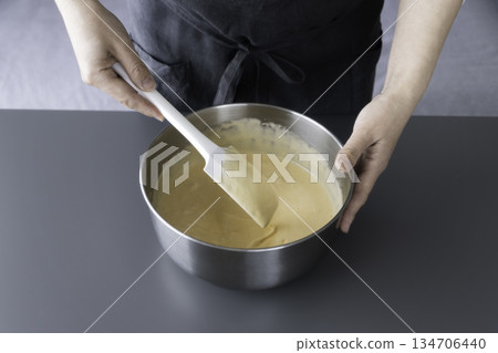 用橡皮刮刀攪拌蛋糕糊。需要不銹鋼碗和操作檯面空間。 134706440