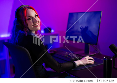 Young female gamer enjoying video games in a neon-lit streaming setup 134706586