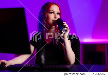 Young woman gaming in a colorful neon-lit studio environment 134706587