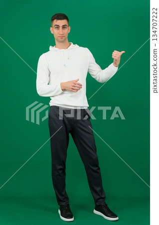 a man points his finger to the left Confident smiling asian man with left hand pointing to his opened right hand palm, isolated on white background. a man points his finger to the left Confident smiling asian man with left hand pointing to his opened right hand palm, isolated on white background. 134707222