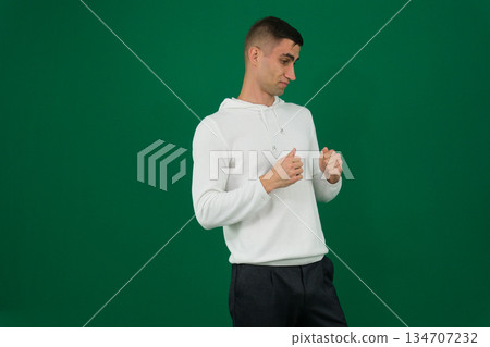 a man holding his hands in fists in front of him young well-groomed european brunette guy with a beard and mustache holds his fists in front of him 134707232