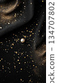 A Single Pearl on a Black Fabric with Golden Glitter 134707802