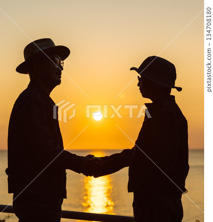 Two people shaking hands at the sea at sunset Two people shaking hands at the sea at sunset 134708180