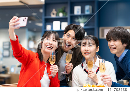 Young men and women taking photos at a party Young men and women taking photos at a party 134708388