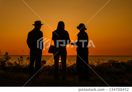 日落時分，三個人在海邊交談。 134708452