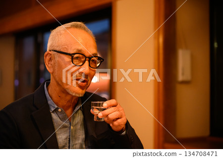 一個戴眼鏡的男人在喝清酒。 134708471