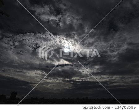 Sunlight shining through gaps in the thick winter clouds Dramatic cloudy sky and city silhouette 134708599